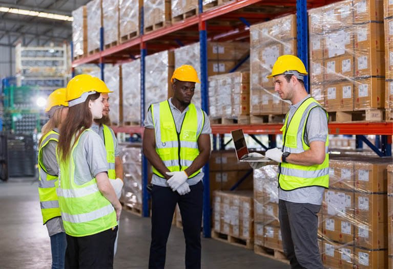 Warehouse workers wearing high-visibility safety workwear in logistics environment